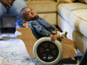 Elijah Jack, 1, looks up from his mobility chair, which was built as a donation by Tulane University students, at his home in New Roads, La., Thursday, Nov. 30, 2023. Tulane science and engineering students are making the second batch of mobility chairs for toddlers, that will eventually go to pediatric patients at Children&rsquo;s Hospital. Wheelchairs are expensive, and insurance won&rsquo;t cover the cost for children unless the child proves they can operate it independently.