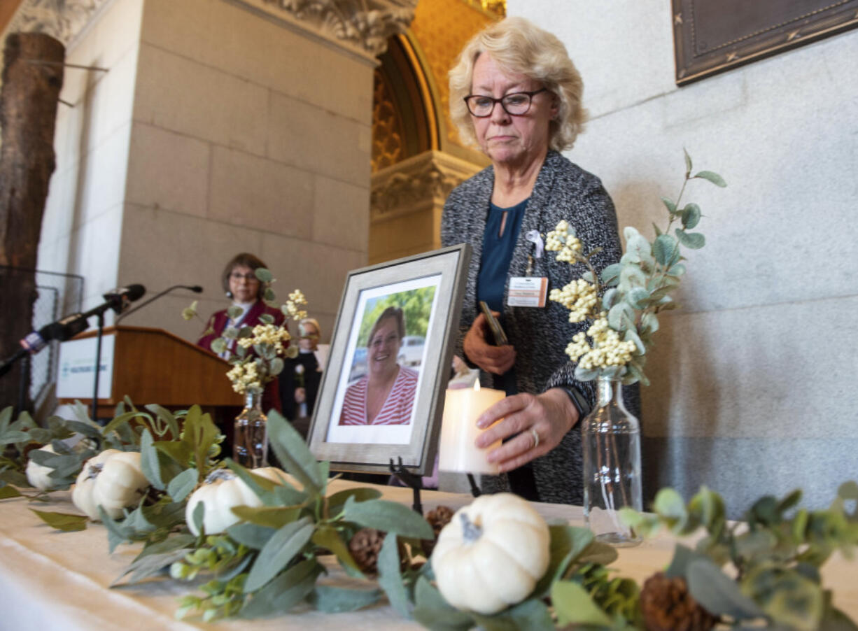 Tracy Wodatch, from Connecticut Association for Healthcare at Home, places a candle next to a photo of Joyce Grayson during the lighting of the candles at a vigil for Grayson at the Connecticut State Capitol&rsquo;s North Lobby on Tuesday, Nov. 28, 2023. , in Hartford, Conn.