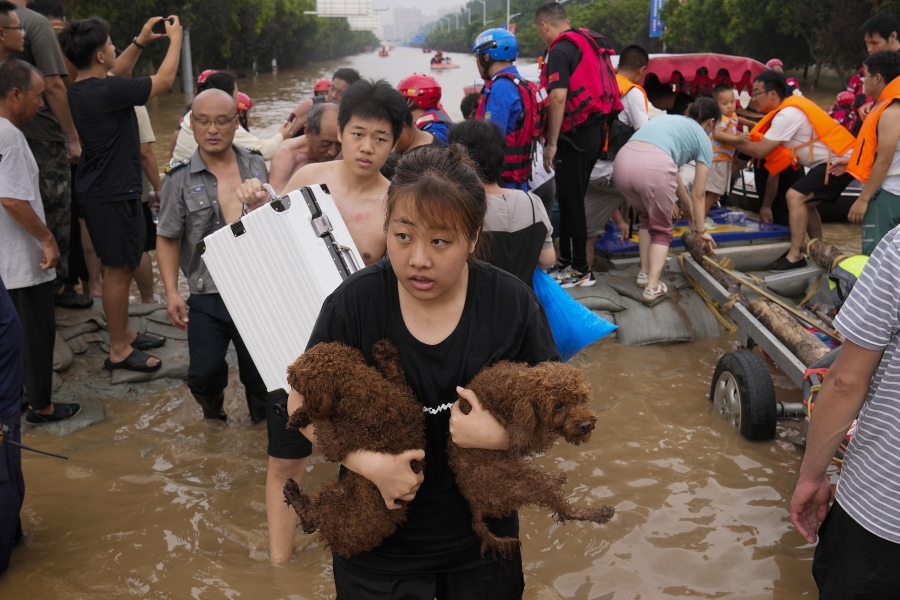 A woman carries her pet dogs as residents are evacuated on rubber boats through floodwaters in Zhuozhou in northern China&rsquo;s Hebei province, south of Beijing, Aug. 2, 2023.