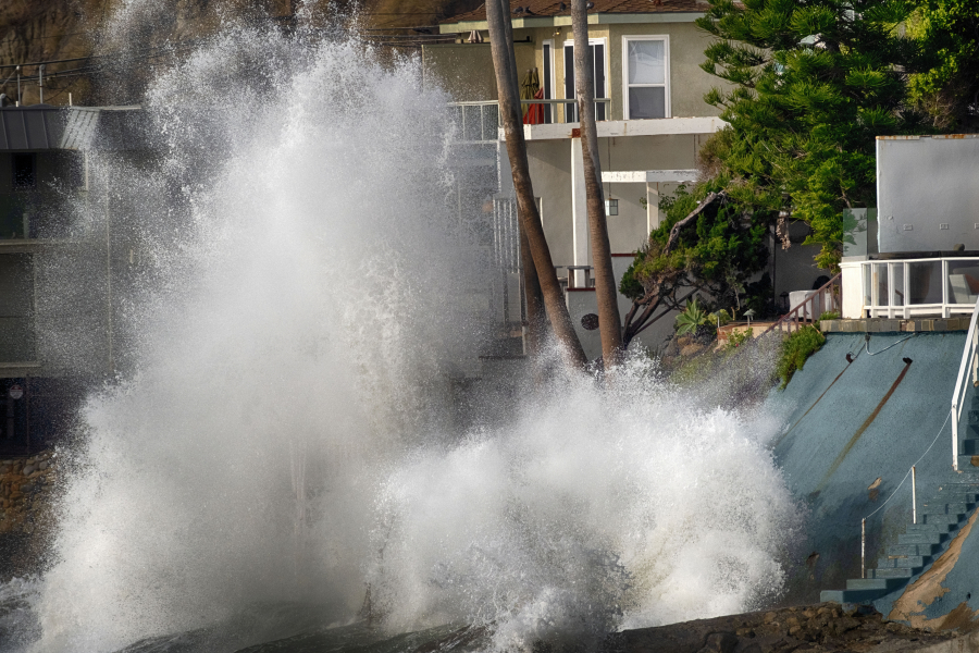 Waves smash against a sea wall next to homes along the California coast in Malibu Beach, Calif., on Friday. Back-to-back storms off the Pacific Ocean will bring rain and snow to Southern California this week, along with the potential for another round of big waves.