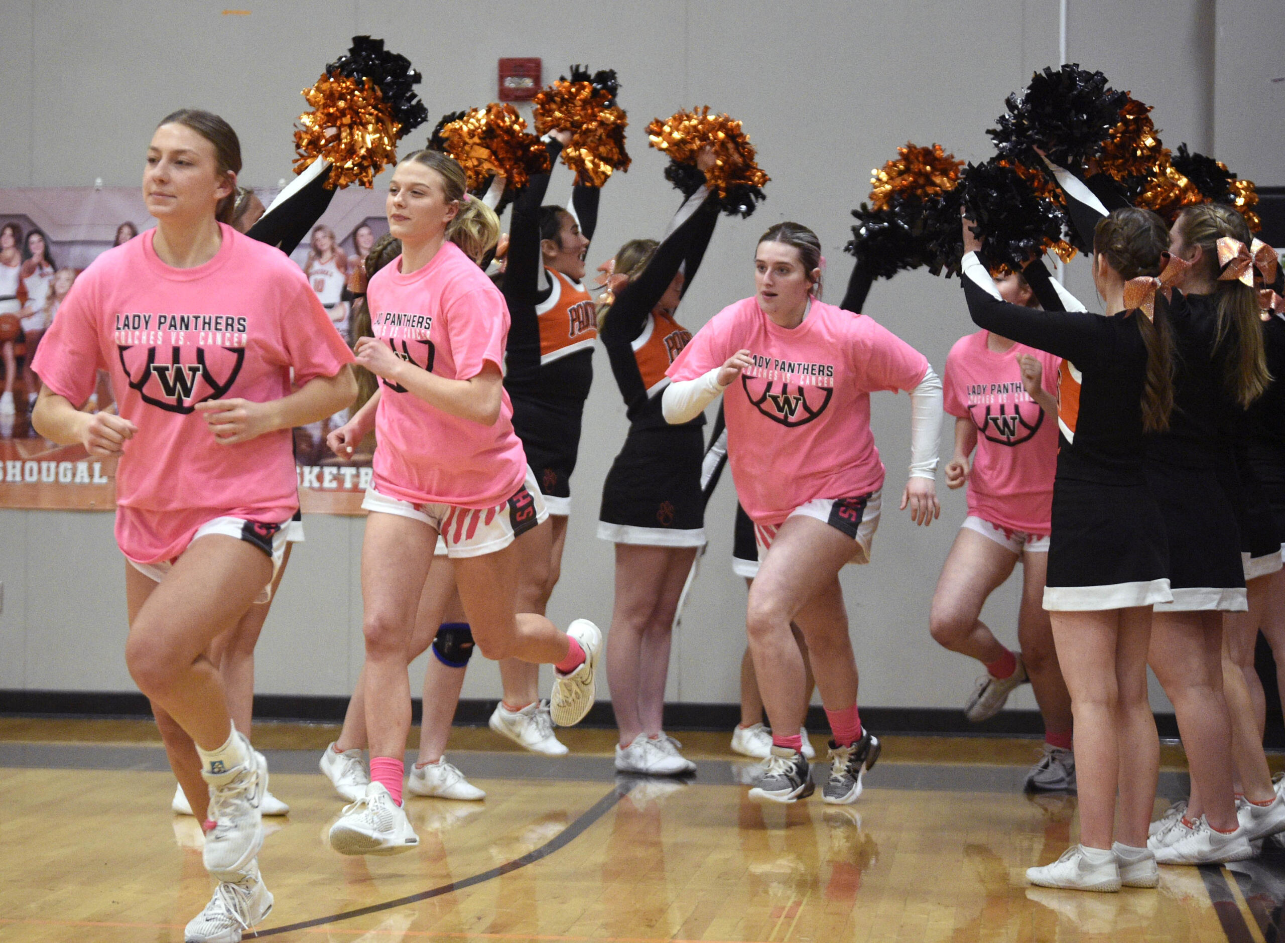 Wearing pink warm-up shirts, Washougal girls basketball players run on to the court prior to the Panthers’ “Coaches vs. Cancer” game against Woodland on Thursday, Jan. 25, 2024, at Washougal High School.