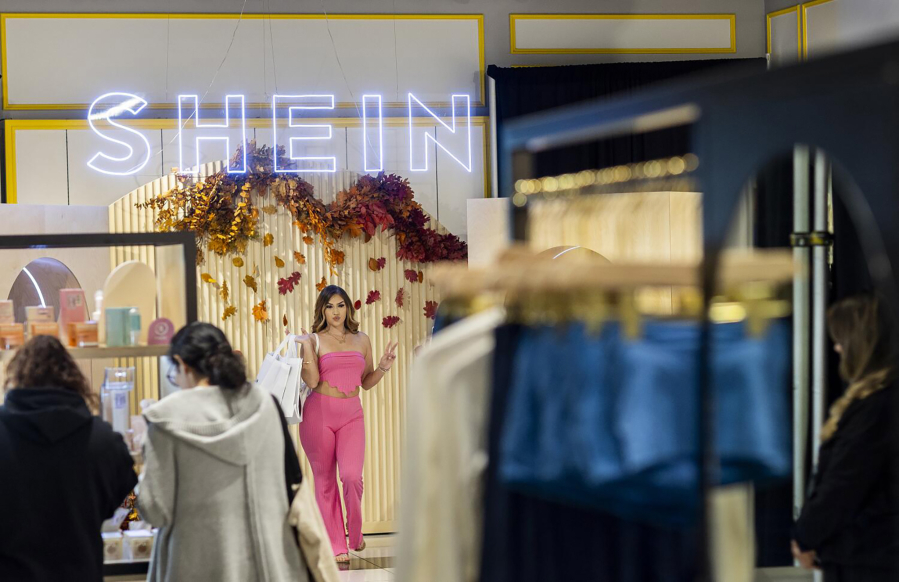 Shoppers pose for photos with their bags of merchandise after being among the first group of shoppers on the opening day of fast fashion e-commerce giant Shein, which is hosting a brick-and-mortar pop up inside Forever 21 at the Ontario Mills Mall in Ontario, California, on Oct. 19, 2023. (Allen J.