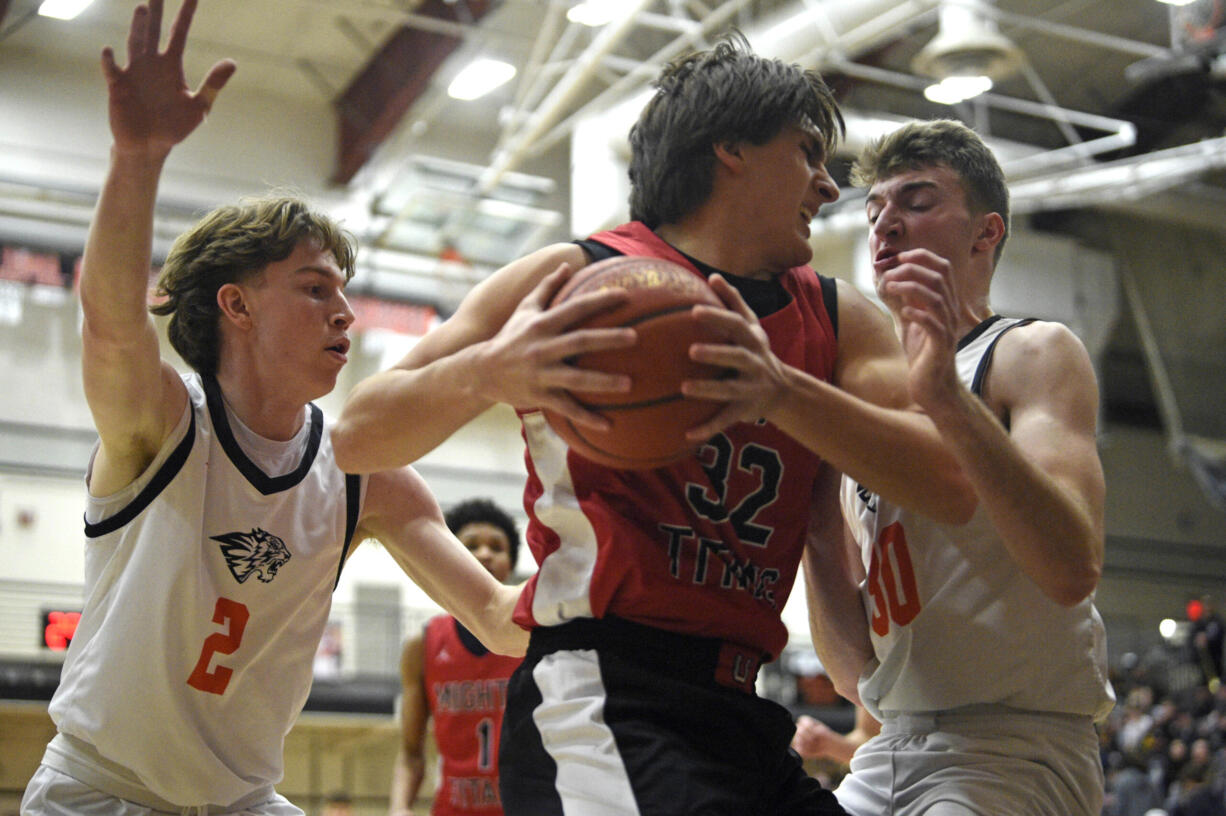 Union’s Nick Burchett, center, grabs a loose ball in the corner against Battle Ground’s Ian Ebinger, left, and Austin Ralphs, right, during a 4A GSHL boys basketball game on Tuesday, Jan. 30, 2024, at Battle Ground High School.