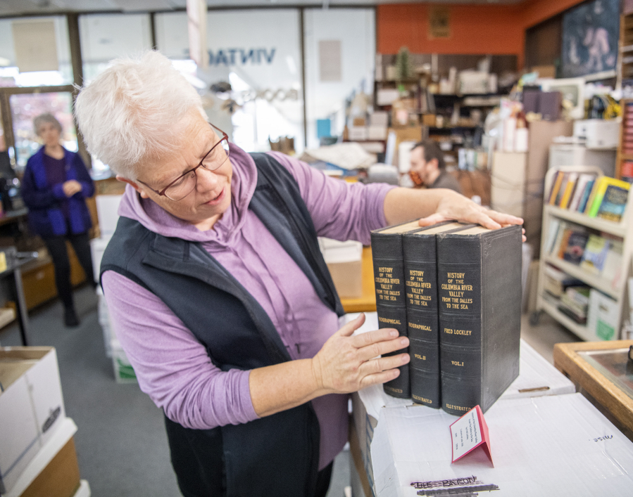 Pepper Parker, a 19-year employee of Vintage Books, shows off a 1928 set of &ldquo;History of the Columbia River Valley: from The Dalles to the Sea&rdquo; at the shop in Vancouver.