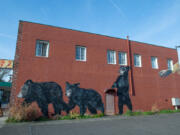 One of Travis London&rsquo;s murals depicts a human hand reaching for three bear cubs on one of downtown Washougal&rsquo;s oldest buildings.
