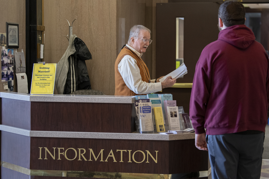 Volunteer Gene Waid, left, lends a hand at the first-floor information desk of the Clark County Courthouse while directing people to where they need to go at the local justice hub on a recent Friday morning. After more than a decade doing a variety of jobs at the courthouse, Waid has become familiar with the myriad things that bring people to the downtown complex.