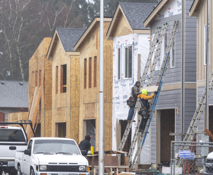 Construction workers move a piece of siding up a ladder on Northeast 138th Avenue in east Vancouver. The construction industry locally and nationally is seeing huge labor shortages, delaying projects and making them more expensive.