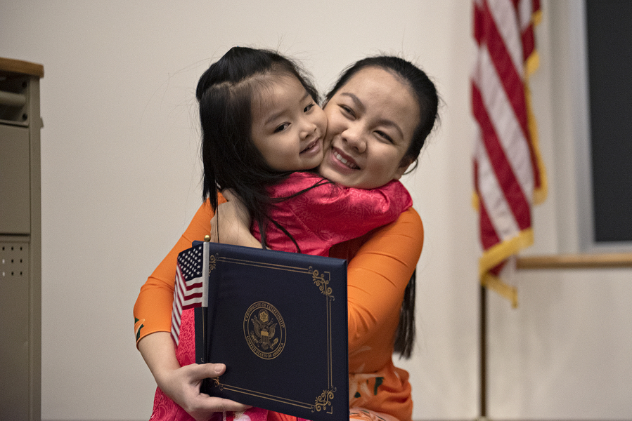 Monica Tran, 3, of Hazel Dell, left, is all smiles while congratulating her mom, Thao Nguyen, who is originally from Vietnam, after she officially became a United States citizen at Washington State University Vancouver on Thursday morning. Nguyen was one of 30 candidates from 19 countries who took part in the naturalization ceremony held in honor of Martin Luther King Jr.