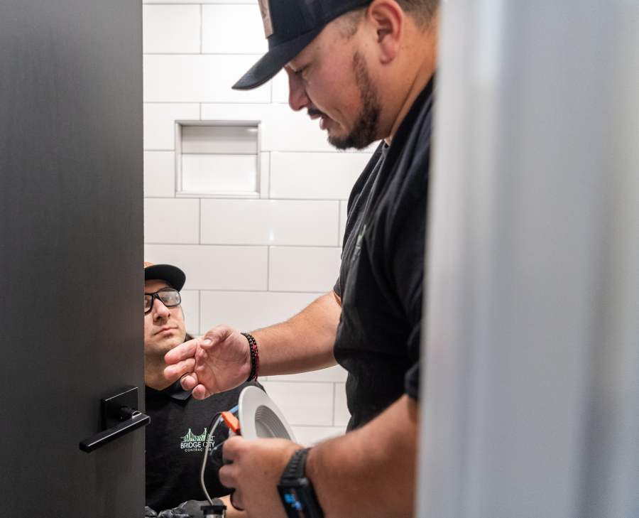 Bridge City Contracting co-founder Roger Gomez, right, talks to certified renovator Kevin Rodriguez while installing a door handle Jan. 19 at a duplex in Vancouver. Construction is an industry that increasingly draws non-English speaking workers.