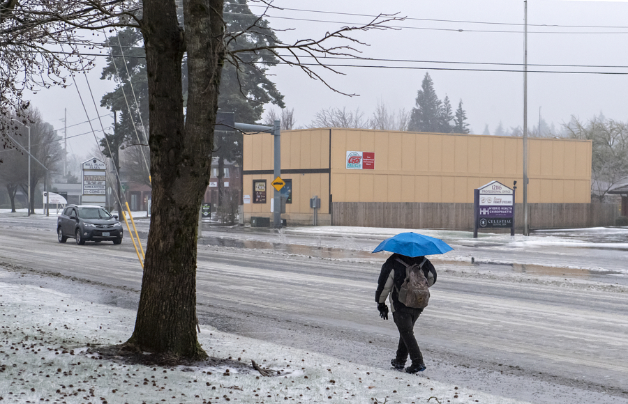 A pedestrian takes shelter under an umbrella as freezing rain transitions to all rain as the temperature rises Wednesday morning, Jan. 17, 2024.