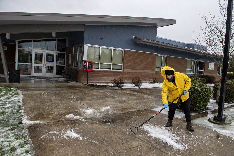 Custodian Mason Rivera of Crestline Elementary School clears ice from the front walkway following a period of winter weather Thursday morning in east Vancouver. The school was closed again for classes Thursday due to a chance of freezing rain in the forecast.