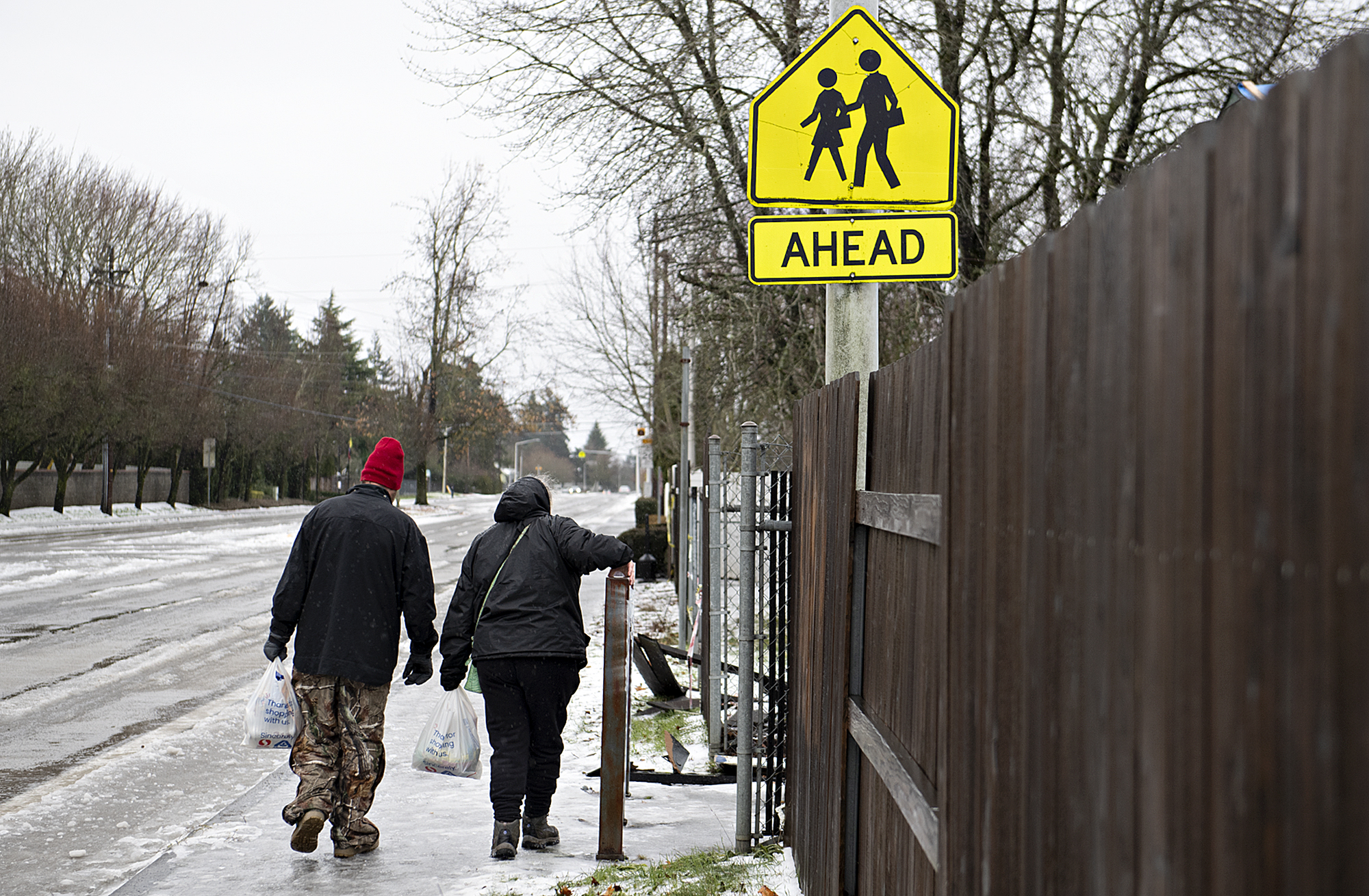 Pedestrians walk carefully along an icy sidewalk near Wy'East Middle School on Thursday morning, Jan. 18, 2024.