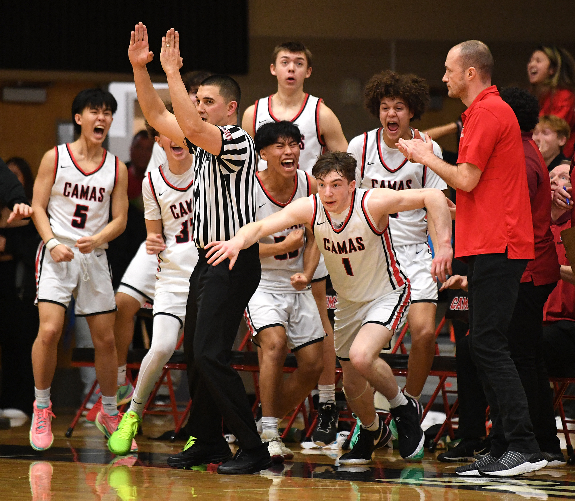 Camas players erupt in celebration around junior Beckett Currie (1) on Tuesday, Jan. 23, 2024, after Currie hit a game-winning three pointer against Skyview at Camas High School. Camas won 69-66.
