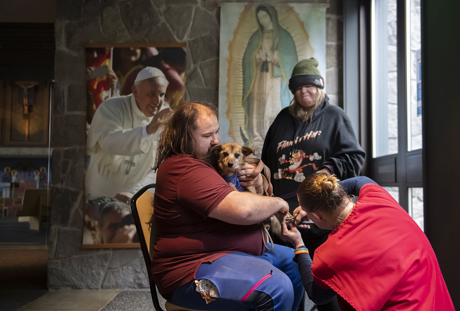 Josiah Rhodes of Vancouver, from left, comforts his four-legged friend, Molly, as she gets a free toenail trim from Christy Gifford of Humane Society for Southwest Washington during Project Homeless Connect Thursday morning at St. Joseph Catholic Church in Vancouver. Rhodes&rsquo; aunt, Cheri Rhodes, watches nearby. The event is the largest resource fair for homeless people in Clark County.