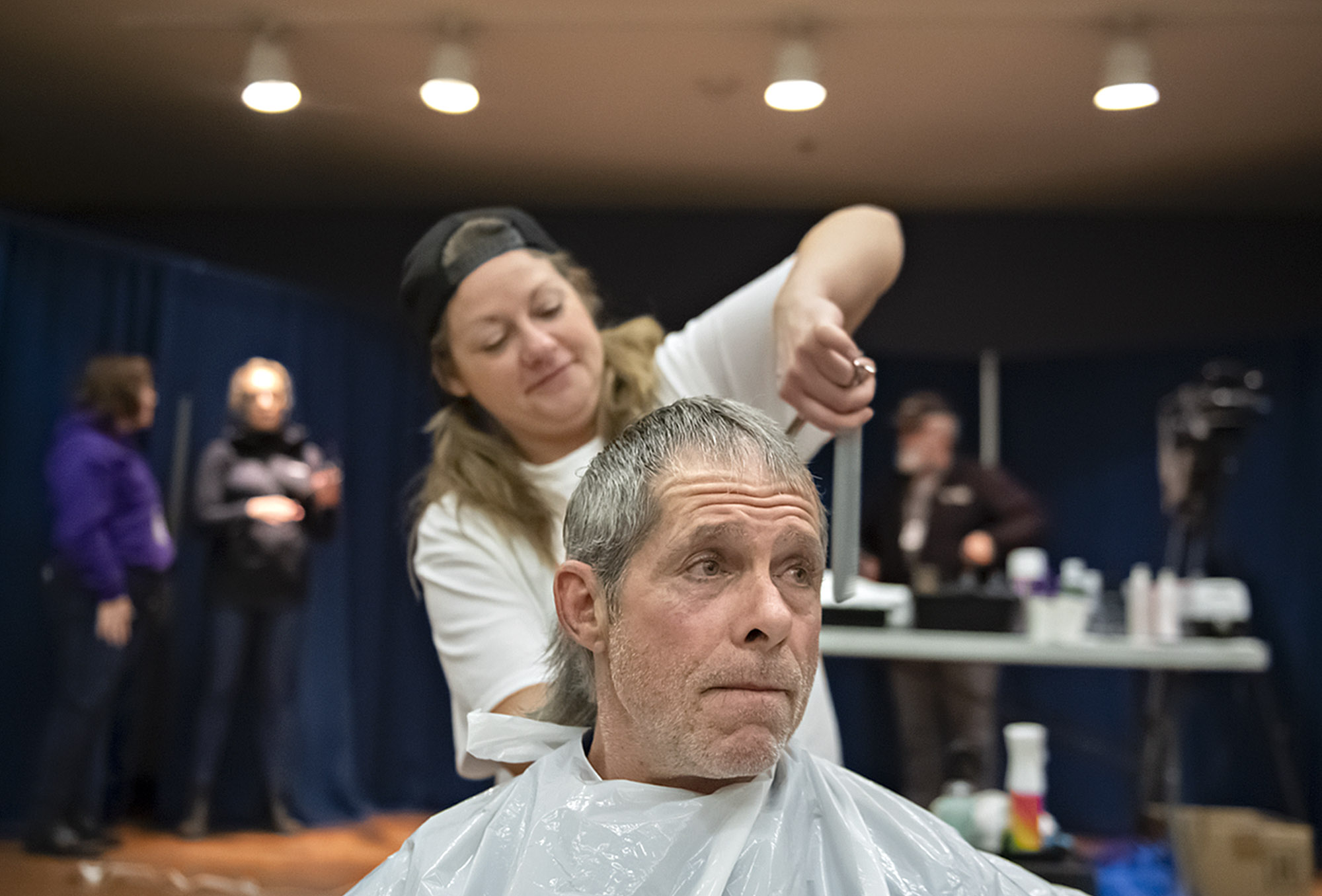 Maggie March of MetroMan Hair Salon in Portland, top, gives Robert Hayes of Vancouver a fresh trim during Project Homeless Connect at St. Joseph Catholic Church on Thursday morning, Jan. 25, 2024.