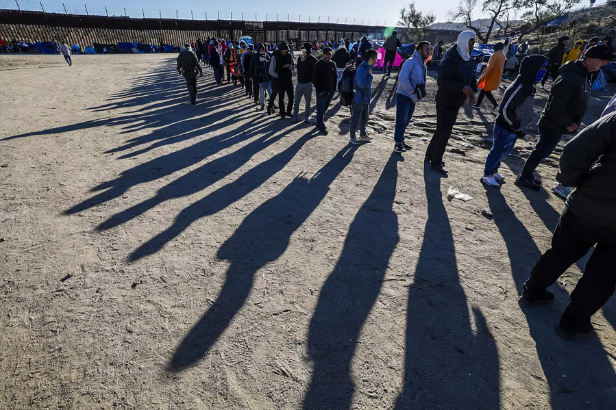Migrants line up for food provided by volunteers at a makeshift camp near the border wall in Jacumba, California.
