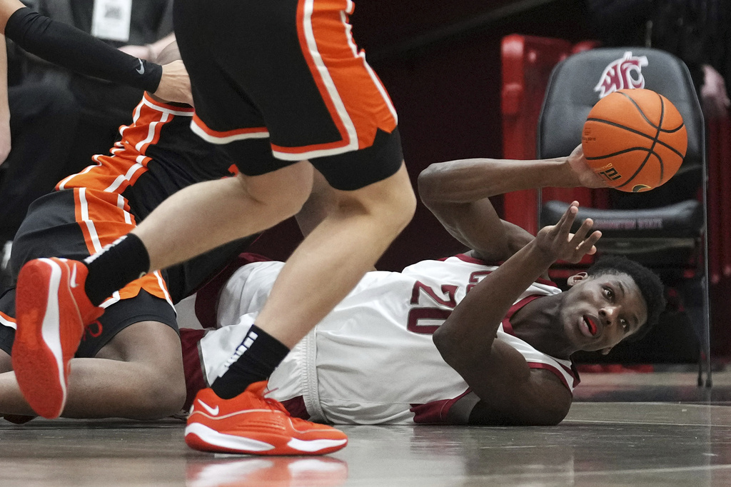 Washington State center Rueben Chinyelu tries to pass the ball after going down against the Oregon State, Thursday, Jan. 4, 2024, during the first half of an NCAA college basketball game in Pullman, Wash. (AP Photo/Ted S.