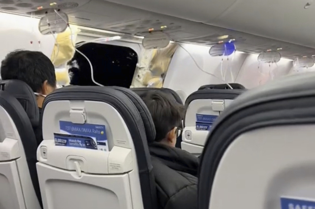 This image from video provided by Elizabeth Le shows passengers near the damage on an Alaska Airlines Boeing 737 Max 9, Flight 1282, which was forced to return to Portland International Airport on Friday, Jan. 5, 2024.