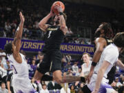Colorado guard J'Vonne Hadley (1) shoots from between Washington guard Koren Johnson (0) and Colorado center Eddie Lampkin Jr., second from right, during the second half of an NCAA college basketball game Wednesday, Jan. 24, 2024, in Seattle. Colorado won 98-81.