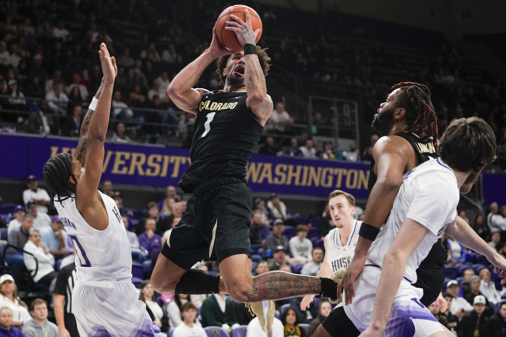 Colorado guard J'Vonne Hadley (1) shoots from between Washington guard Koren Johnson (0) and Colorado center Eddie Lampkin Jr., second from right, during the second half of an NCAA college basketball game Wednesday, Jan. 24, 2024, in Seattle. Colorado won 98-81.
