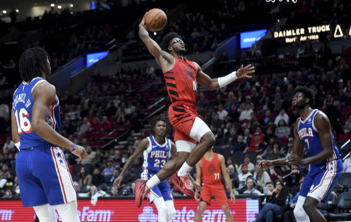 Blazers guard Scoot Henderson, center, goes up for a dunk against Philadelphia 76ers guard Ricky Council IV (16) and center Mo Bamba (7) during the second half of an NBA basketball game in Portland, Ore., Monday, Jan. 29, 2024.