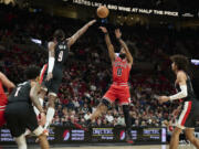 Chicago Bulls guard Coby White, right, shoots a jump shot against Portland Trail Blazers forward Jerami Grant, left, during the first half of an NBA basketball game in Portland, Ore., Sunday, Jan. 28, 2024.