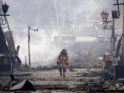 A firefighter walks through the rubble and wreckage of a burnt-out marketplace following earthquake in Wajima, Ishikawa prefecture, Japan Tuesday, Jan. 2, 2024. A series of powerful earthquakes in western Japan damaged homes, cars and boats, with officials warning people on Tuesday to stay away from their homes in some areas because of a continuing risk of major quakes and tsunamis.