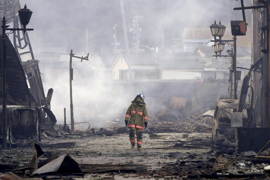A firefighter walks through the rubble and wreckage of a burnt-out marketplace following earthquake in Wajima, Ishikawa prefecture, Japan Tuesday, Jan. 2, 2024. A series of powerful earthquakes in western Japan damaged homes, cars and boats, with officials warning people on Tuesday to stay away from their homes in some areas because of a continuing risk of major quakes and tsunamis.