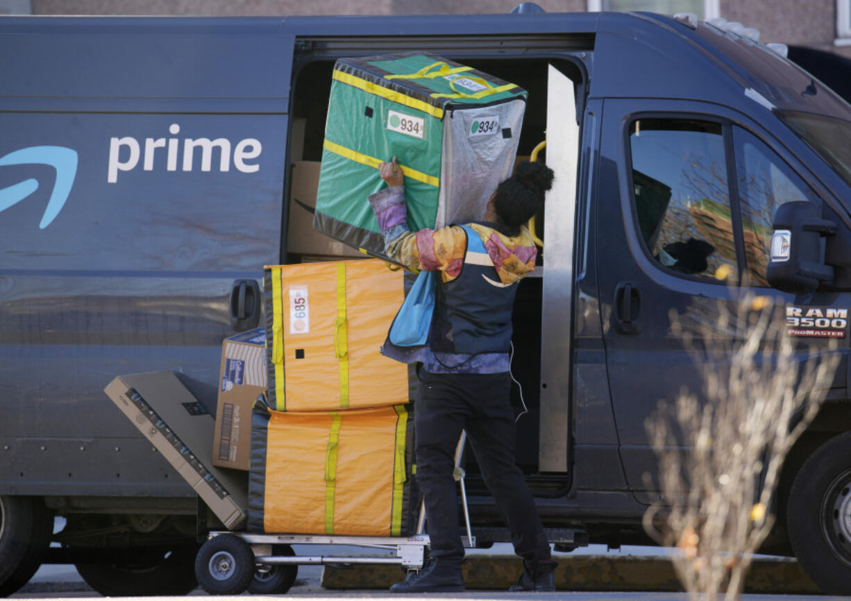 FILE - An Amazon Prime delivery person lifts packages while making a stop at a high-rise apartment building, Nov. 28, 2023, in Denver. Amazon delivered packages to its Prime customers at the fastest speeds ever in 2023, the retailer said Tuesday, Jan. 30, 2024, thanks to better inventory placement, a new regionalization model for shipments and more same-day warehouses.