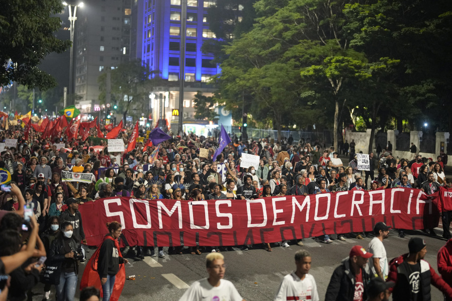 FILE - Supporters of Brazil&rsquo;s President Luiz In&aacute;cio Lula da Silva march holding a banner with a message that reads in Portuguese: &ldquo;We are a democracy&rdquo;, during a protest calling for protection of the nation&rsquo;s democracy, in Sao Paulo, Brazil, Jan. 9, 2023.  The march was called on the day after a riot led by supporters of outgoing President Jair Bolsonaro destroyed government buildings in the capital Brasilia in an alleged bid to forcefully restore Bolsonaro to office.