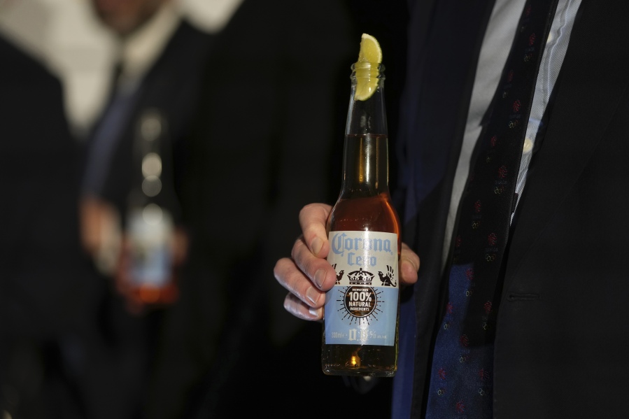 A guest holds a bottle of Corona Cero Alcohol Free Beer at a news conference in London, Friday, Jan. 12, 2024. The International Olympic Committee has signed Anheuser-Busch InBev as the first beer brand in the 40-year history of its sponsorship program, which earns billions of dollars for the organization and international sports.