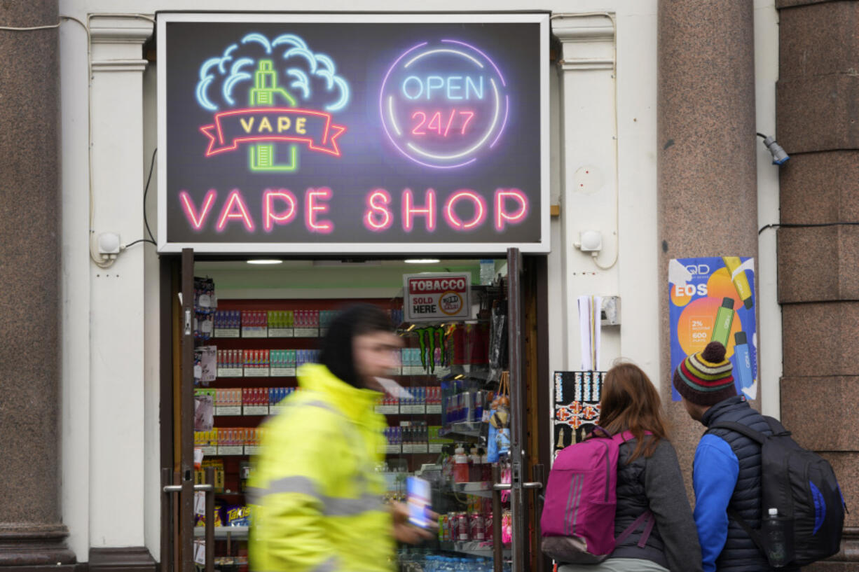 Pedestrians pass a vape shop in London, Monday, Jan. 29, 2024. The British government says it will ban the sale of disposable vapes and limit their cornucopia of flavors in an effort to prevent children becoming addicted to nicotine. It also says it will stick to a contentious proposal to ban today&rsquo;s young people from ever buying cigarettes.
