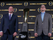 Washington head coach Kalen DeBoer, left, and Michigan head coach Jim Harbaugh pose with the national championship trophy on Sunday in Houston. (Godofredo A.