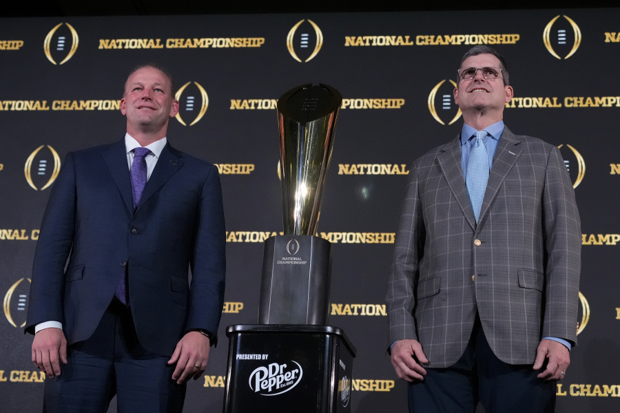 Washington head coach Kalen DeBoer, left, and Michigan head coach Jim Harbaugh pose with the national championship trophy on Sunday in Houston. (Godofredo A.