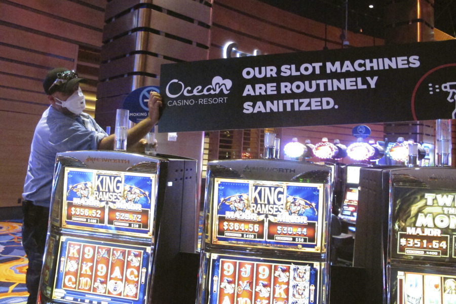 This June 3, 2020, photo shows a worker at the Ocean Casino Resort in Atlantic City, N.J., installing a sign indicating that slot machines will routinely be sanitized once the casino reopened a month later to prevent the spread of the coronavirus. On Jan. 24, 2024, the New Jersey Supreme Court rejected an attempt by the casino to collect on a business interruption policy for the 3 1/2 months it was closed due to the pandemic.
