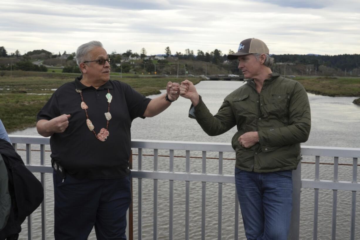 California Gov. Gavin Newsom fist-bumps Wiyot Tribal Chair Ted Hernandez at the Elk River where they were touring a salmon restoration project in Eureka, Calif., Monday, Jan. 29, 2024.