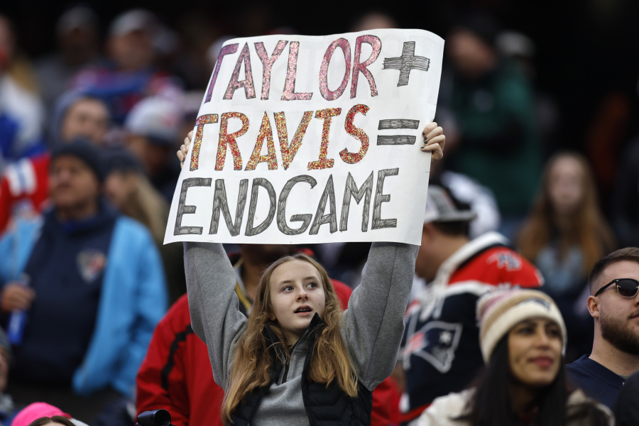 FILE - A fan displays a sign that calls attention to Taylor Swift and Kansas City Chiefs tight end Travis Kelce during the second half of an NFL football game between the Chiefs and the New England Patriots, Sunday, Dec. 17, 2023, in Foxborough, Mass.