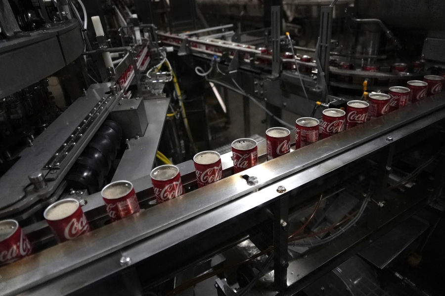 File - Coca-Cola cans move down a conveyer belt in the Swire Coca-Cola bottling plant on Oct. 20, 2023, in Denver. On Thursday, the government issues the first of three estimates of GDP growth in the United States during the October-December quarter.