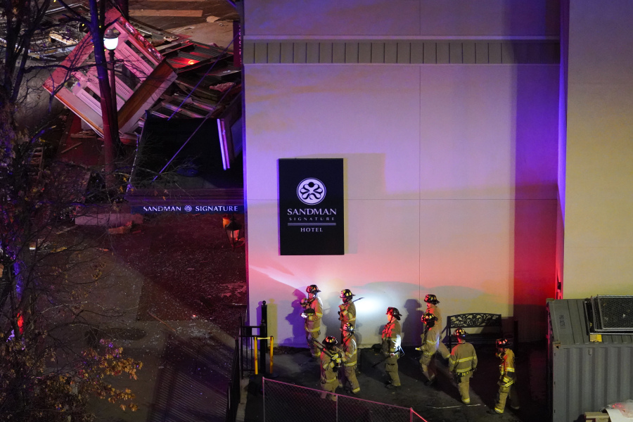 Damage, top left, is seen as firefighters exit the Sandman Signature hotel following an explosion earlier in the day, Monday, Jan. 8, 2024, in Fort Worth, Texas.