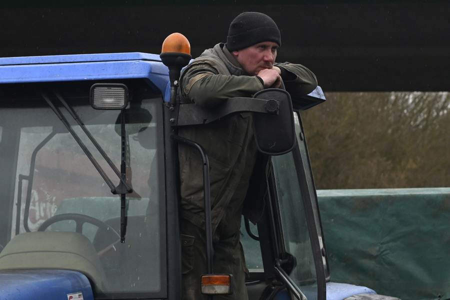 A French farmer stands on his tractor as farmers block a highway, Tuesday, Jan. 23, 2024 near Beauvais, northern France. Farmers have for months been protesting for better pay and against what they consider to be excessive regulation, mounting costs and other problems.
