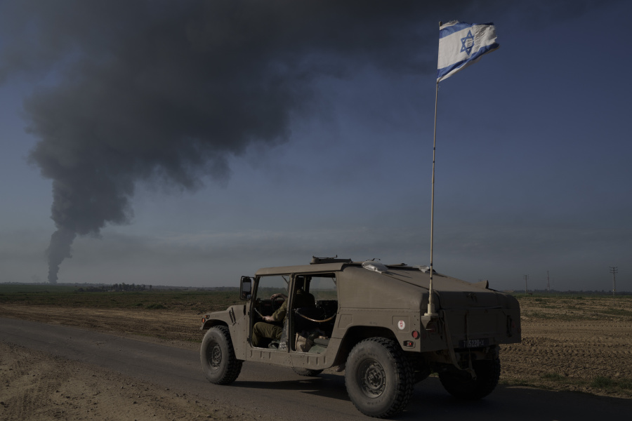 Israeli soldiers travel near the Israeli-Gaza border as smoke rises to the sky in the Gaza Strip, seen from southern Israel, Sunday, Jan. 21, 2024.