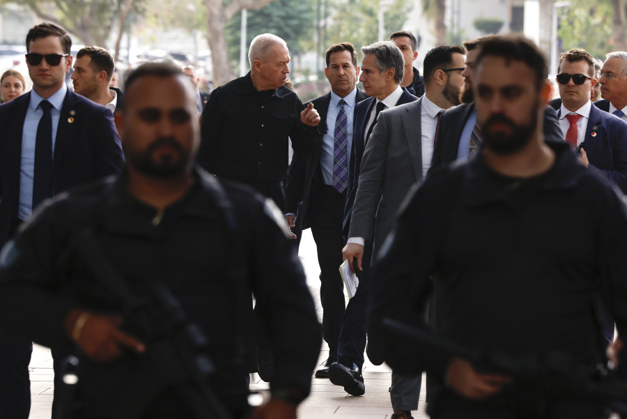 Officers with guns walk in front of U.S. Secretary of State Antony Blinken and Israeli Minister Benny Gantz as they meet, during his week-long trip aimed at calming tensions across the Middle East, at the Kirya, in Tel Aviv, Israel, Tuesday, Jan. 9, 2024.