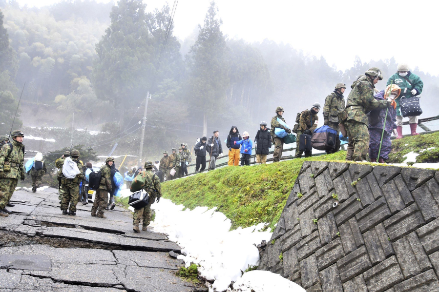 In this photo provided by Japanese Ministry of Defense, residents are evacuated with the help of Japanese Self Defense Force members, as their district was isolated by the earthquakes, in Wajima, Ishikawa prefecture, Japan, Wednesday, Jan. 3, 2024.