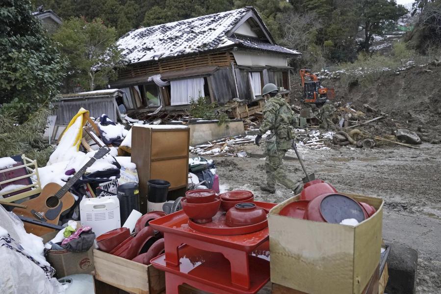 Housewares are gathered outside a fallen house as a member of Japan Self Defense Force searches the area in the earthquake-hit Suzu, Ishikawa prefecture, Monday, Jan. 8, 2024. Thousands of people made homeless overnight are living in weariness and uncertainty on the western coast of Japan a week after powerful earthquakes hit the region.