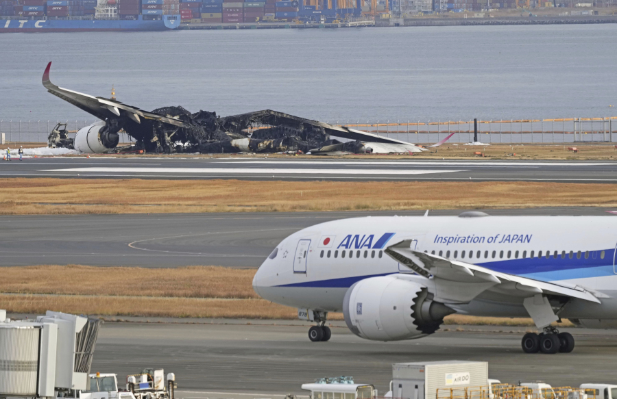 The burn-out Japan Airlines plane is seen, at rear, at Haneda airport on Wednesday, Jan. 3, 2024, in Tokyo, Japan. The large passenger plane and a Japanese coast guard aircraft collided on the runway at Tokyo&rsquo;s Haneda Airport on Tuesday and burst into flames, killing several people aboard the coast guard plane, officials said.