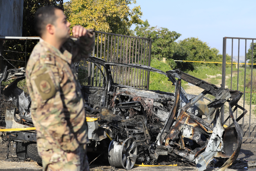 A Lebanese army officer stands next of a destroyed car in the southern town of Bazouriyeh, Lebanon, Saturday, Jan. 20, 2024. An Israeli drone strike on the car near the Lebanese southern port city of Tyre killed two people, the state-run National News Agency reported.