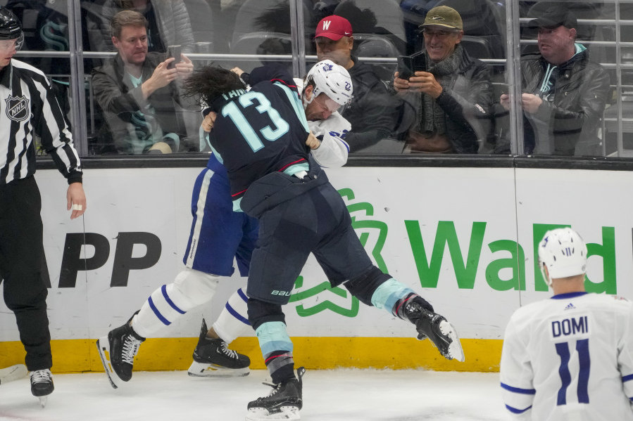Toronto Maple Leafs defenseman Jake McCabe (22) and Seattle Kraken left wing Brandon Tanev (13) fight during the first period of an NHL hockey game Sunday, Jan. 21, 2024, in Seattle.