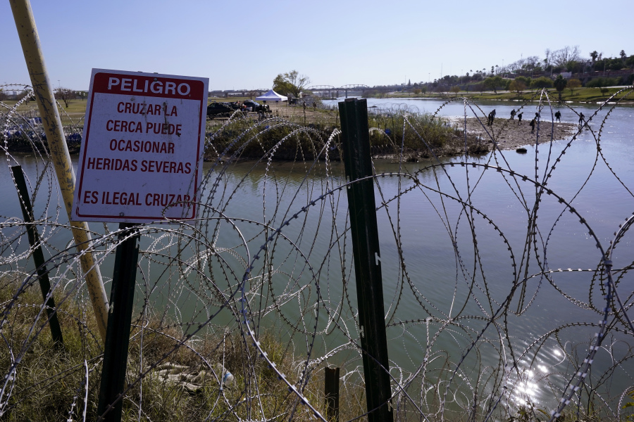Migrants cross the Rio Grande into the U.S. from Mexico behind Concertina wire and a sign warning that it&#039;s dangerous and illegal to cross, Wednesday, Jan. 3, 2024, in Eagle Pass, Texas. According to U.S. officials, a Mexican enforcement surge has contributed to a sharp drop in illegal entries to the U.S. in recent weeks.