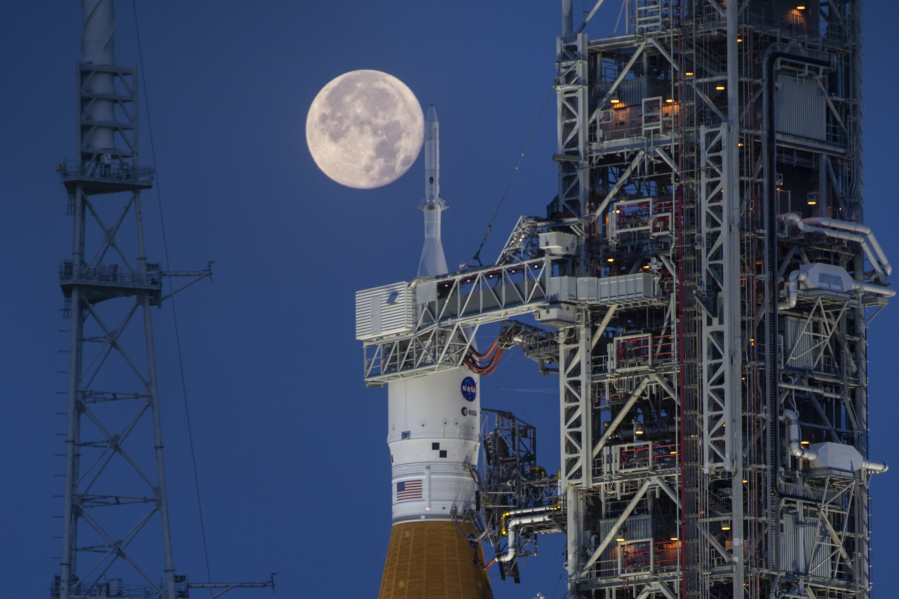 A full moon is seen behind the Artemis I Space Launch System (SLS) and Orion spacecraft, atop the mobile launcher, are prepared for a wet dress rehearsal to practice timelines and procedures for launch, at Launch Complex 39B at NASA&rsquo;s Kennedy Space Center in Florida on June 14, 2022. On Tuesday, Jan. 9, 2024, NASA said astronauts will have to wait until 2025 before flying to the moon and another few years before landing on it.