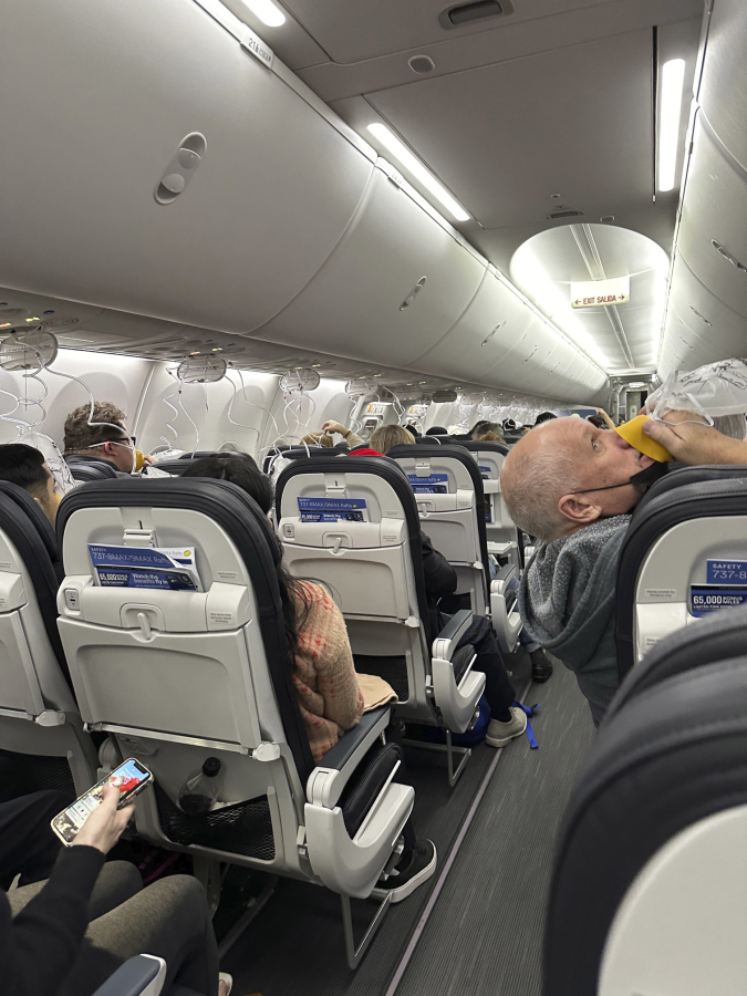 This image provided by Kelly Bartlett shows passengers with oxygen masks on an Alaska Airlines Boeing 737 Max 9, Flight 1282, which was forced to return to Portland International Airport on Friday, Jan. 5, 2024.